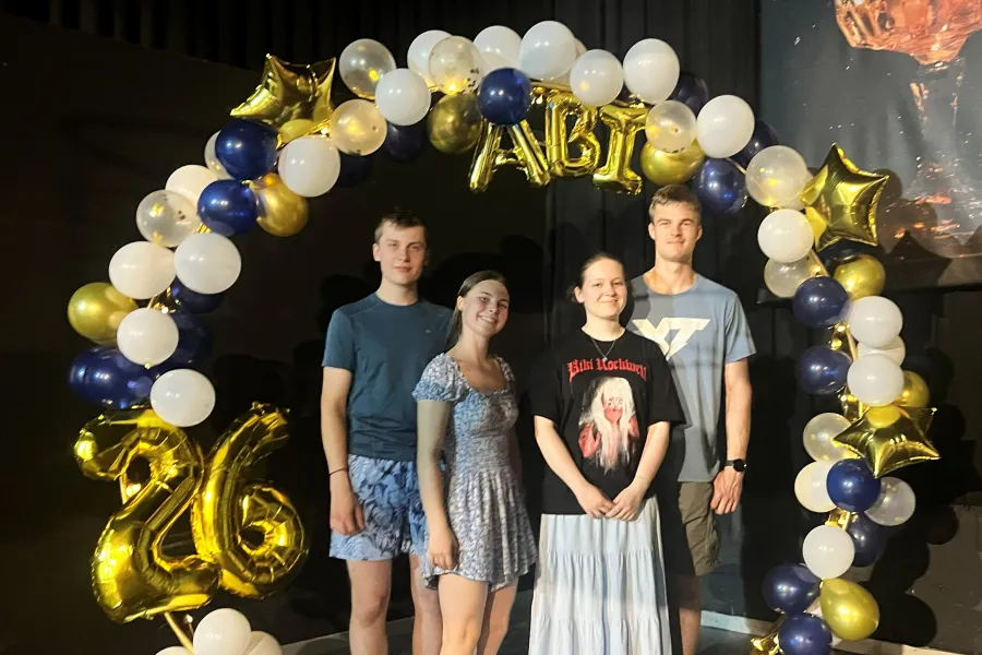 Vier Abiturientinnen und Abiturienten unter dem Ballonbogen „ABI 26“ in Navy, Gold und Weiß