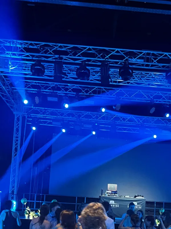 Bühne mit blauer Lichtshow und DJ, davor die Tanzfläche