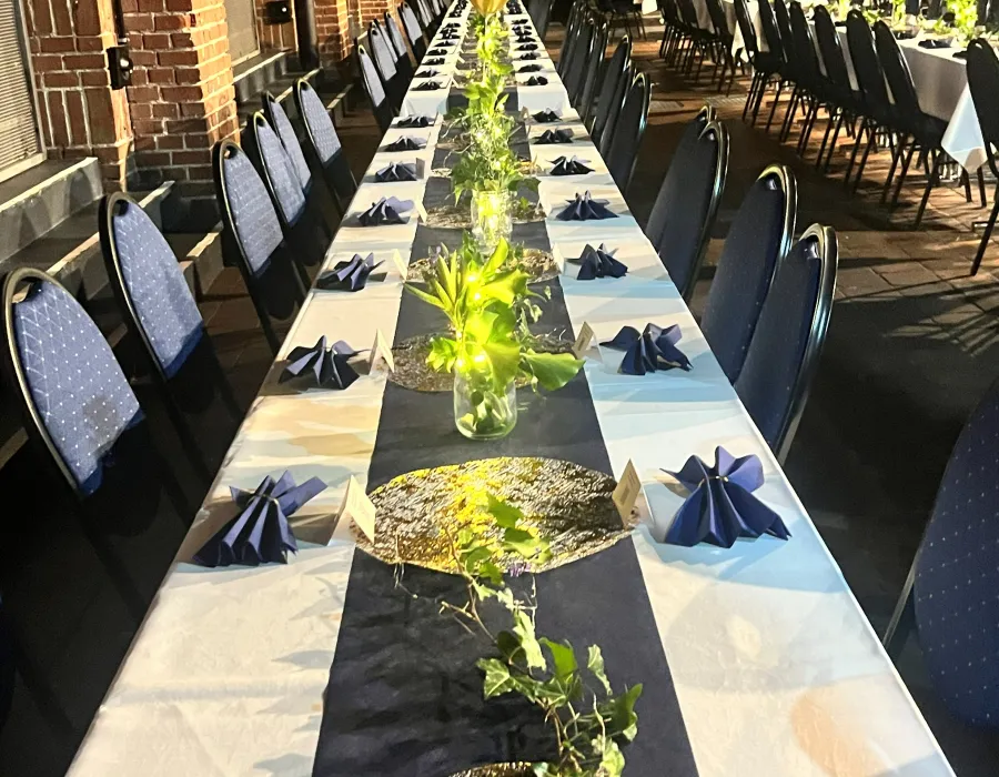 Lange Festtafel mit goldenen Platztellern, Navy-Servietten und Grün